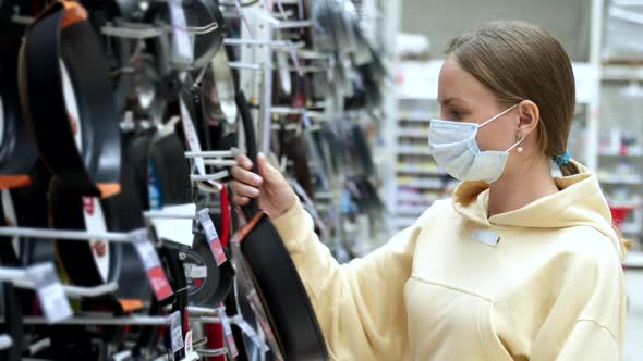 Woman in the Mask in the Store Chooses a Frying Pan . The Concept of Shopping for a Home