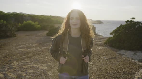 Slow motion shot of happy redheaded woman walking at coast, Ibiza