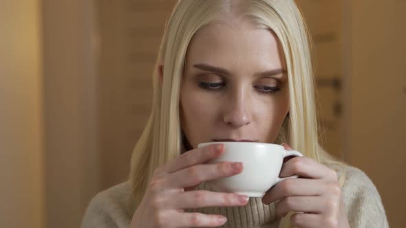 Fashionable Young Blonde Woman Drinking Coffee on a Cafe