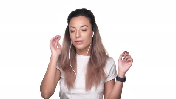 Portrait of Relaxed Satisfied Woman Listening to Music with Earphones and Dancing Over White