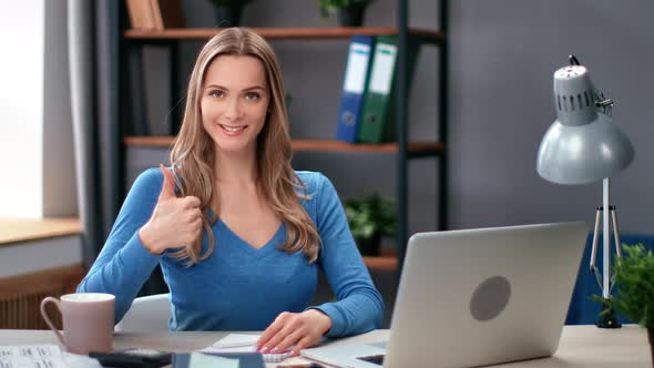 Portrait Happy Young Blonde Business Woman Posing at Comfortable Workplace Showing Cool Thumb Up