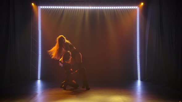 Two Young Women Go Go Dancers with Long Hair Erotically Dance in a Dark Studio with Staged Light