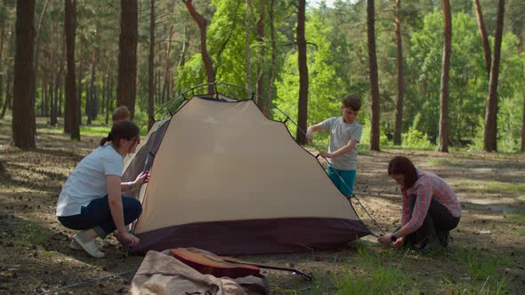 Two women and two boys having summer camping vacation in forest. Mothers and sons