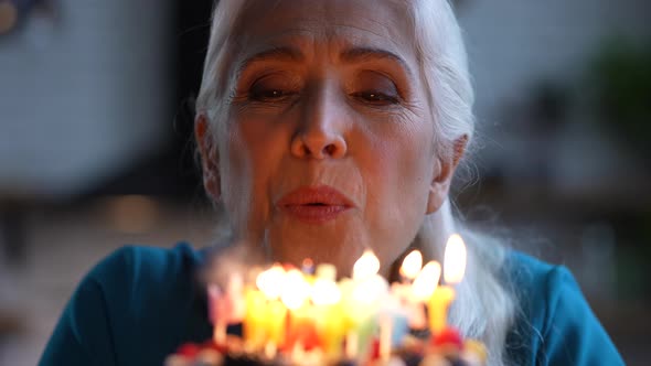 Smiling Aged Birthday Girl Blowing Candles on Cake