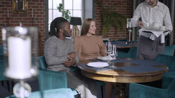 Relaxed Carefree Couple Dating in Restaurant Talking As Waiter Bringing Afternoon Tea in Slow Motion