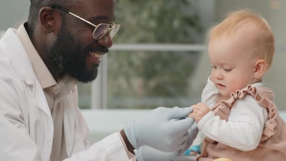 African American Pediatrician Playing with Baby during Health Checkup