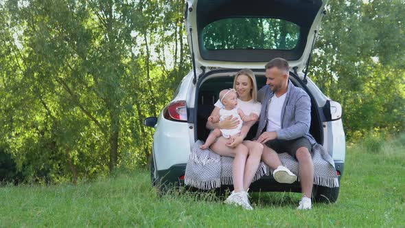 Traditional Family with Baby Girl Resting Outside the City Sitting in the Trunk of a Car