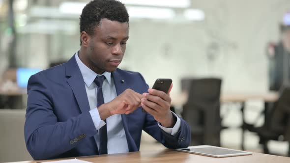 Attractive African Businessman Using Smartphone in Office