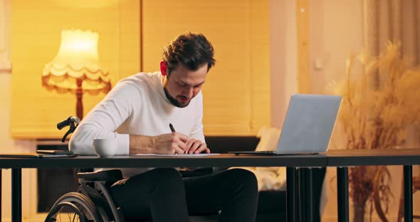 Disabled Caucasian Handsome Man in a White Turtleneck in Wheelchair Working in Loft Office Man