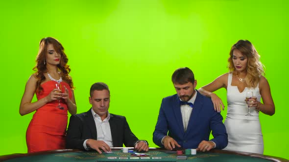 Two Pairs of Young People Playing Cards at Poker Table