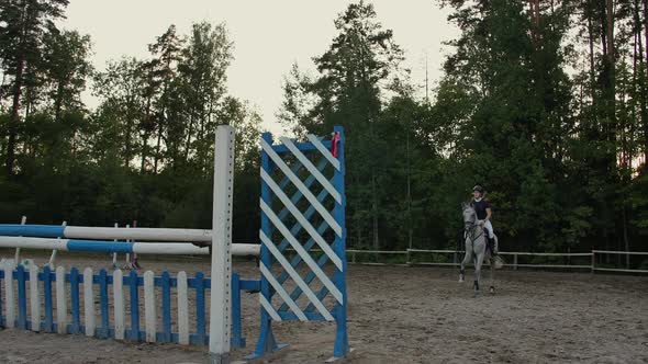 Young Female Rider on Bay Horse Jumping Over Hurdle on Equestrian Sport Competition
