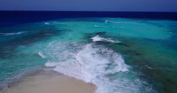 Wide overhead clean view of a sandy white paradise beach and blue sea background in colorful 4K