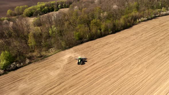 Aerial view large tractor cultivating a dry field. Top down aerial view tractor cultivating ground alt