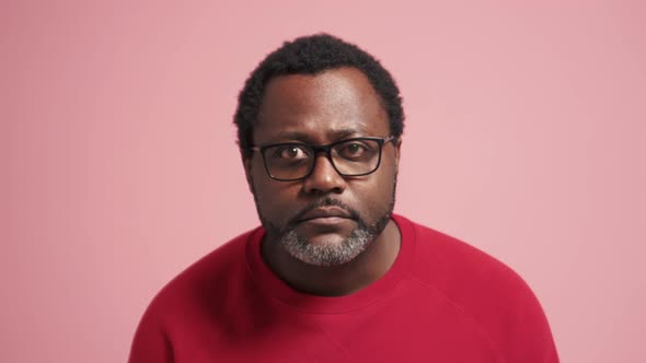 Serious adult African man peering at the camera and showing silence gesture