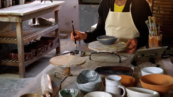 Attentive male potter painting on bowl