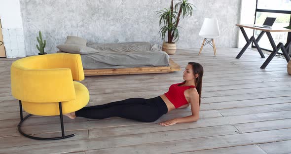 Woman Goes in for Sports Works Out at Home in Bedroom Against Background of Bed, Uses Yellow Chair