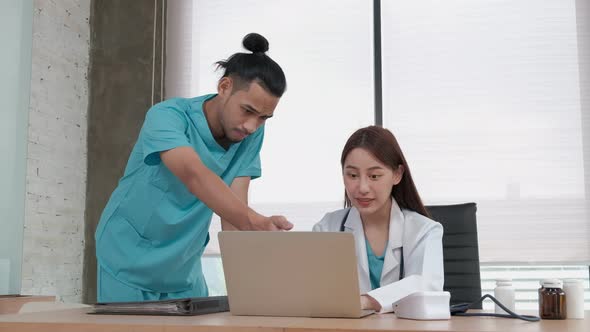 Two uniformed young doctors work in medical clinic office.