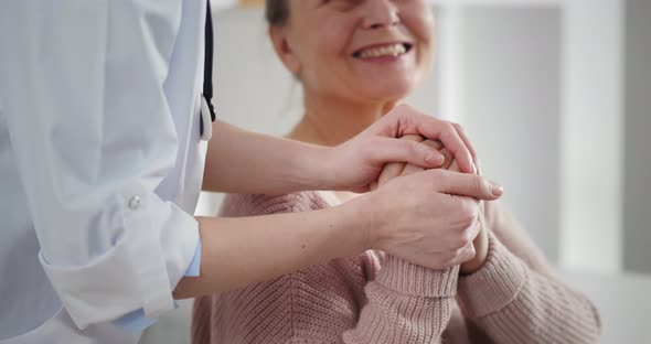 Female Doctor in Office Reassuring Senior Female Patient and Holding Her Hands