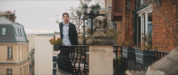 Young man thoughtful standing on the balcony on a cloudy day