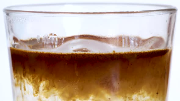 Macro shot of instant coffe powder dissolving into hot water in a transparent glass, macro shot clos
