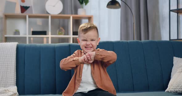 Small Boy in Cozy Apartment and Depicting Anger on His Face when Looking into Camera