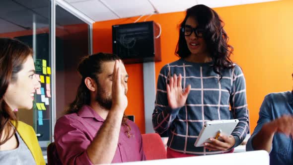 Smiling graphic designers giving high five during meeting