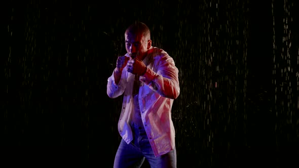 a Man in Jeans and an Unbuttoned White Shirt Strikes with Hands in Streams of Water on a Dark