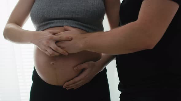 Detail of mother in advanced pregnancy and future father feeling baby's moves. Shot with RED helium