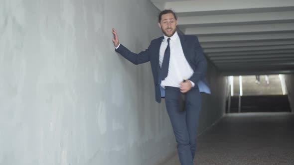 Wide Shot Portrait of Drunk Caucasian Businessman Walking with Wine Bottle Along Underground