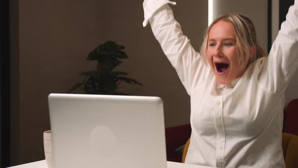 Excited Young Woman Winner Looks at Laptop Celebrates Online Success Sits at Home