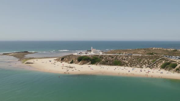 Aerial view around the lighthouse in Vila Nova de Milfontes, sunny Portugal - orbit, drone shot