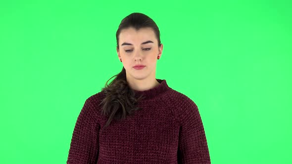 Upset Girl Guilty Lowers Her Eyes on a Green Screen in the Studio.