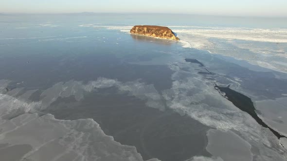 Drone View of a Rocky Island Among the Ice-covered Winter Sea