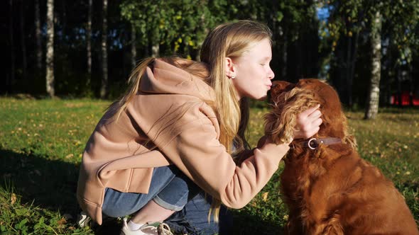 Teenager Girl with Long Loose Fair Hair Pets and Kisses Dog