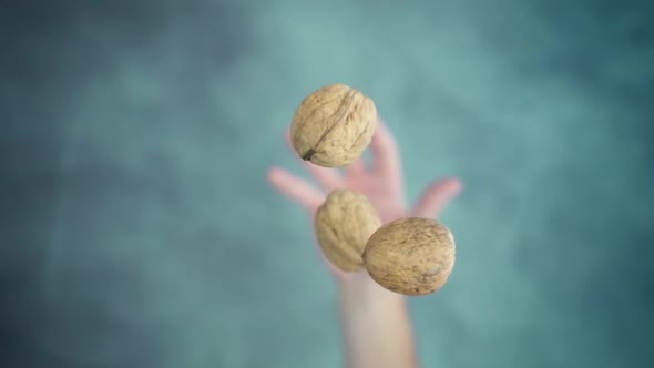 Hand Throwing Up and Catching Walnuts in Thick Shells