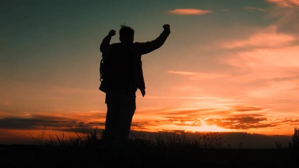 Man stands with raised hands on rock