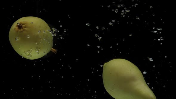 Slow Motion Two Pear Falling Into Transparent Water on Black Background