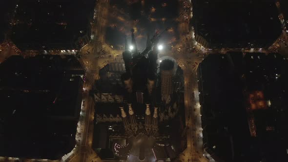 AERIAL: Close Overhead Drone Shot of La Sagrada Familia at Night with Beautiful City Traffic Lights 