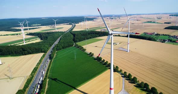 Wind turbine farm and high speed road with traffic between agricultural fields.