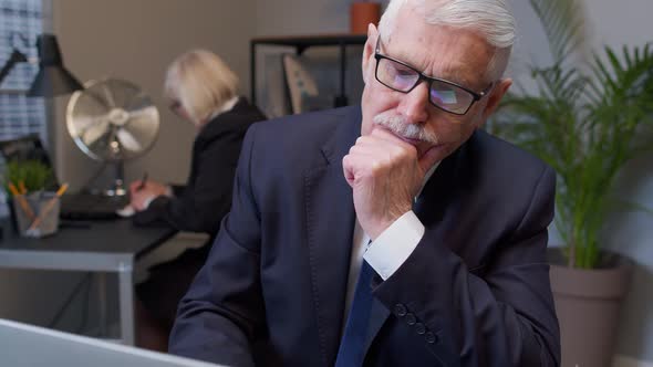 Thoughtful Senior Businessman Grandfather Working on Laptop in Office Wondering Difficult Solution