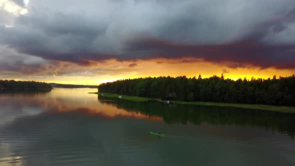 Young male is paddling just before a rain storm is about to hit while beautiful sunset is forming in