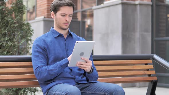 Young Man Using Tablet While Sitting on Bench