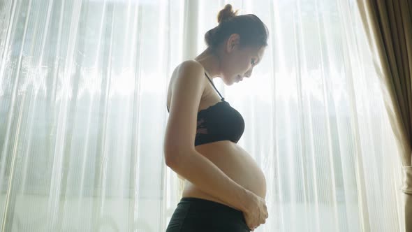 Asian young beautiful pregnancy woman holding and stroking her tummy.