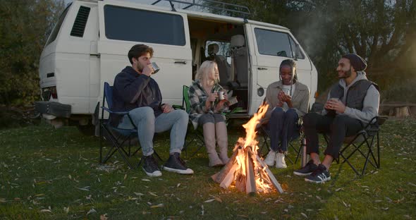 Tourists Drinking Tea From Flask By Fire