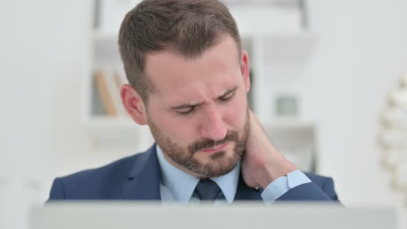 Portrait of Businessman with Laptop Having Neck Pain