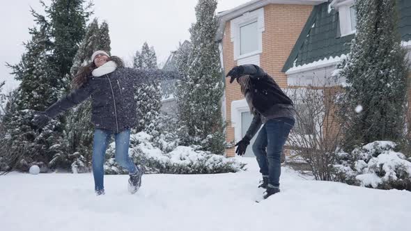 Happy Father and Daughter Tossing Snow Playing Snowballs Outdoors on Backyard in Slow Motion