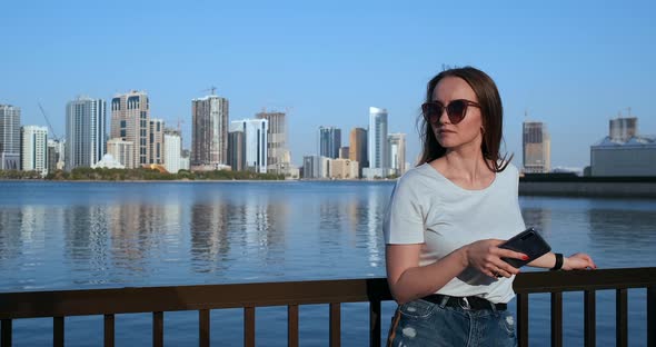 A Girl with Long Hair Dials a Message on the Smartphone at the Quay of Dubai