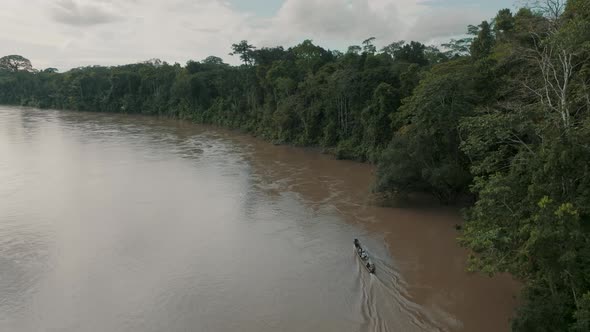 Aerial View Of Travelling Canoe Across A River In The Green Jungle Of Ecuador. Drone Shot