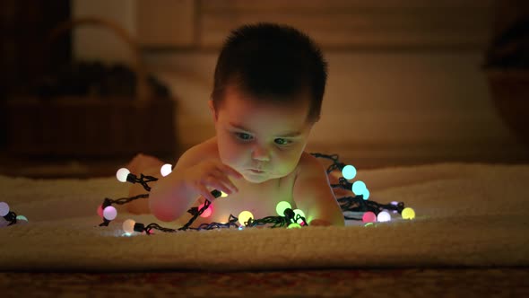 Baby playing with light garland on Christmas Day