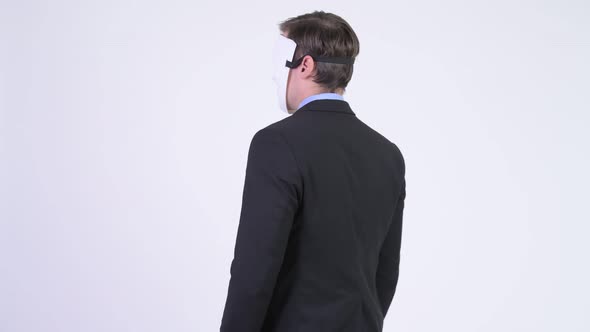 Rear View of Young Businessman Wearing White Mask with Arms Crossed